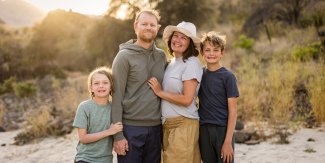 A family on a sandy riverside beach in Idaho smiling and posing for a photo
