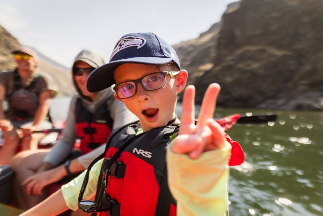 little boy giving peace sign on river